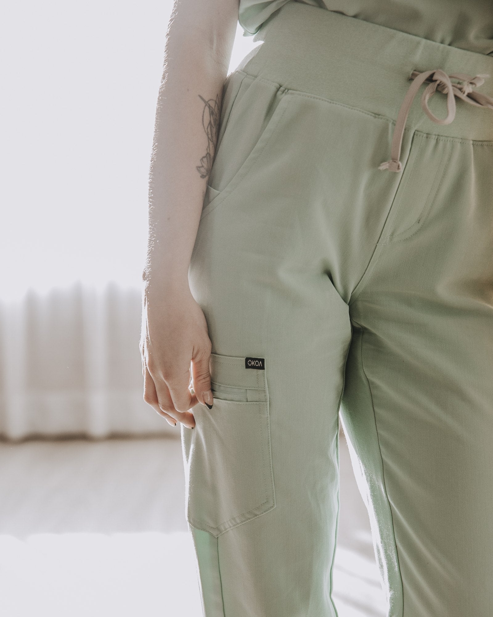 Drawstring and cargo pocket detail on sage KOA high rise scrub joggers