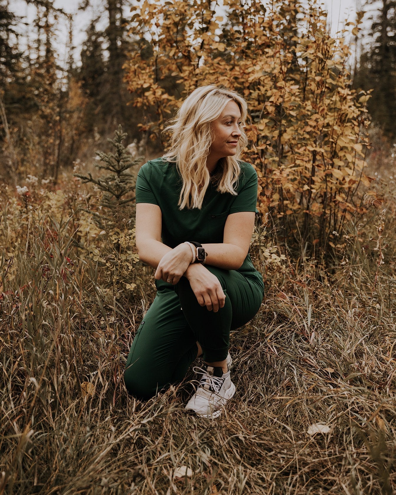 Forest green KOA One Pocket scrub top and matching joggers, worn outdoors