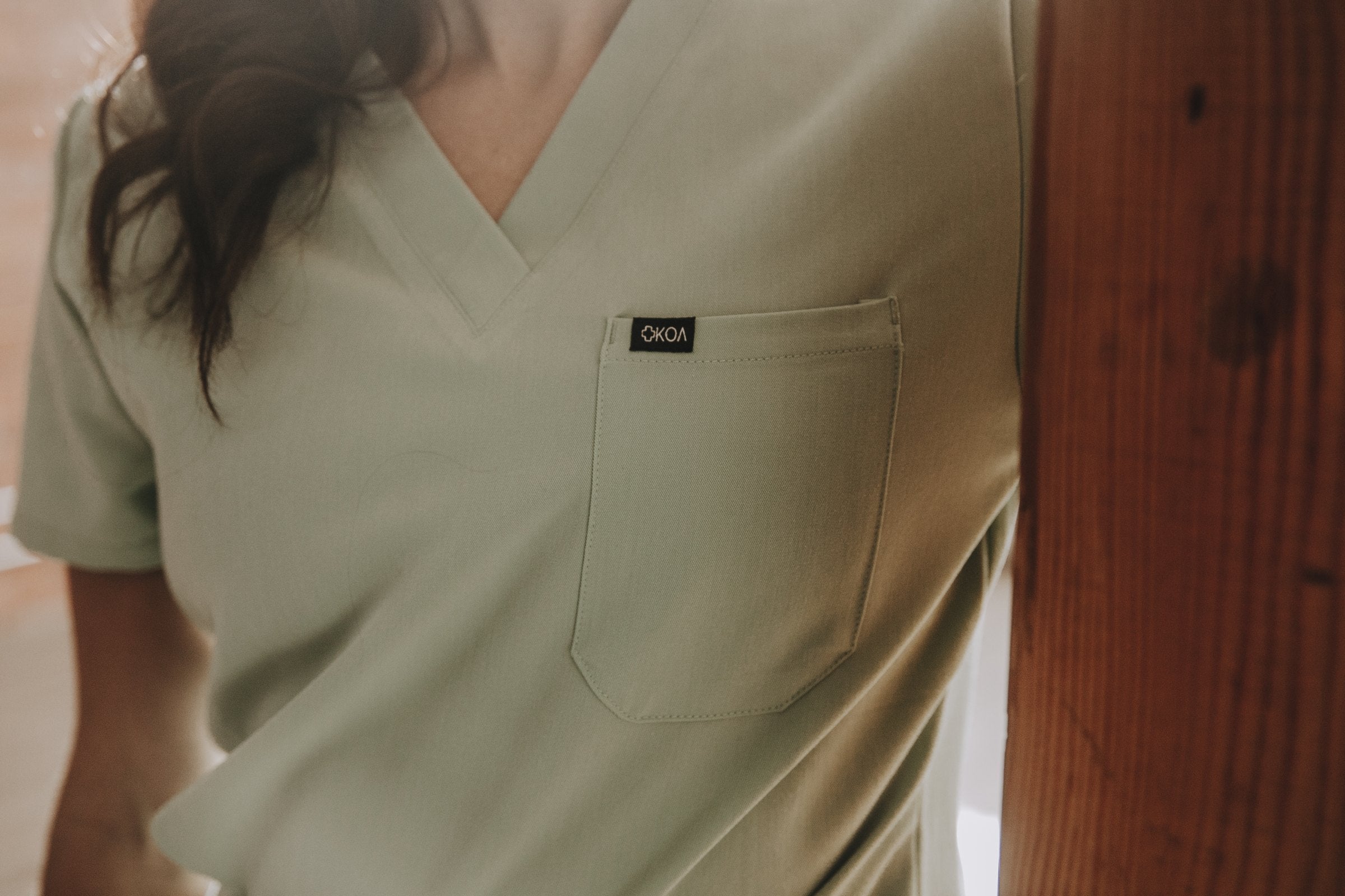 Close-up of the chest pocket and KOA label on a sage KOA scrub top